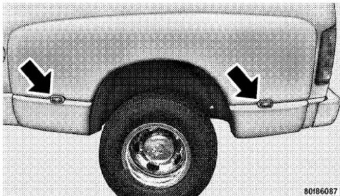 Close-up of a car's front wheel and side panel, showing two black arrows pointing to the rear wheel (no text or symbols present)