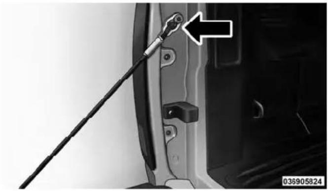 Close-up of a car door panel with a black cable inserted, showing a mechanical component and an arrow pointing to the handle (no text or symbols visible)