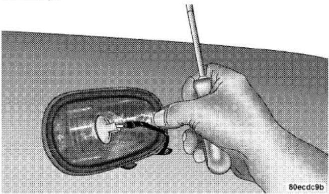 Hand inserting a small component into a car's door panel, no text or symbols visible