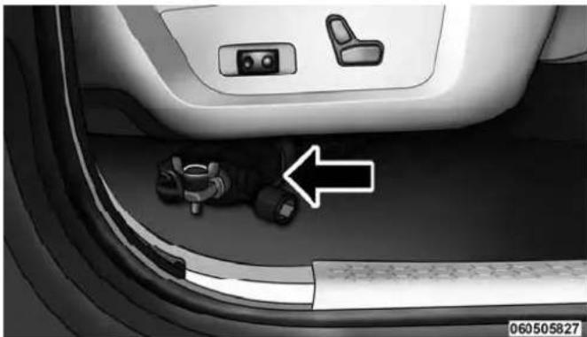 Interior view of a car showing seatbelt and dashboard components with an arrow pointing to a small object (no text or symbols visible)
