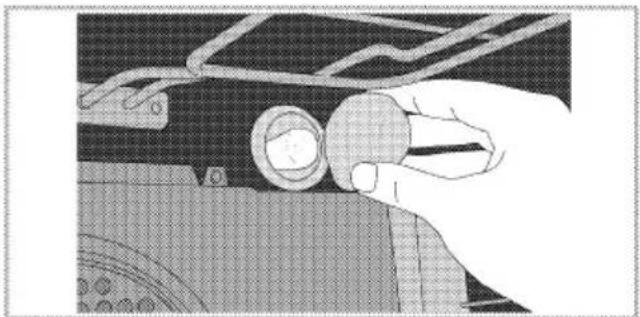 Illustration of a hand holding a circular component over a mechanical component (no text or symbols visible)
