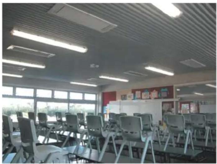 Interior view of a classroom with desks, chairs, and ceiling lights (no visible text or symbols)