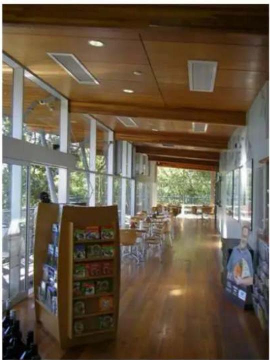 Interior view of a modern, empty library or reading room with wooden ceiling beams, bookshelves, and large windows (no visible text or signage)