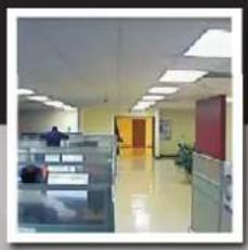 Interior view of an empty office hallway with cubicles and desks (no visible text or signage)