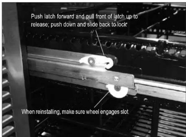 Push latch forward and pull front of latch up to release; push down and slide back to lock When reinstalling, make sure wheel engages slot