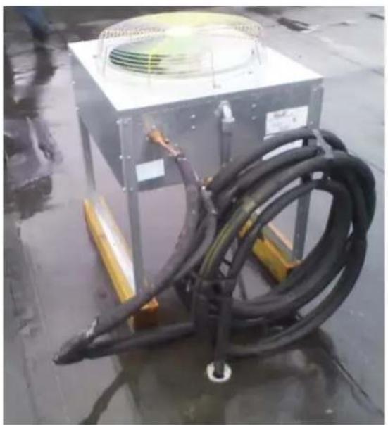 Industrial equipment setup with coiled black hoses and a square fan on a metal frame, placed on a wet floor (no visible text or symbols)