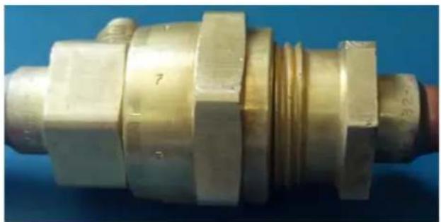 Close-up of a brass mechanical component with threaded end and hexagonal flanges (no visible text or symbols)