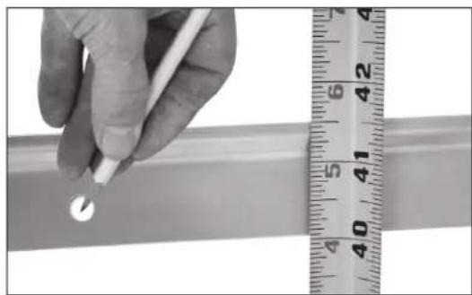 Close-up of a hand holding a white object next to a ruler, showing measurement scale (no text or symbols visible)