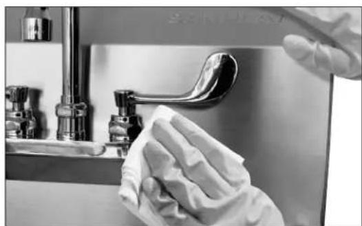 Close-up of a hand cleaning a stainless steel faucet with a cloth (no text or symbols visible)