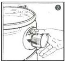 Hand holding a small cylindrical object with a knob, next to a circular container (no text or symbols visible)