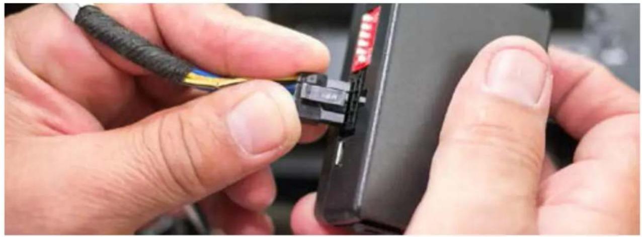 Close-up of hands installing a black cable connector into a device (no visible text or symbols)