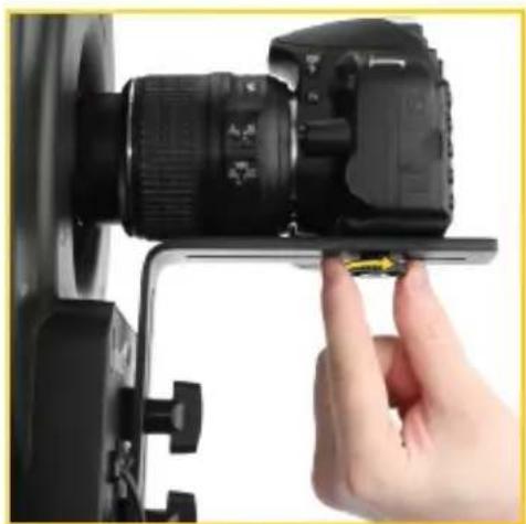 Close-up of a hand adjusting a camera lens mounted on a flat stand (no visible text or symbols)