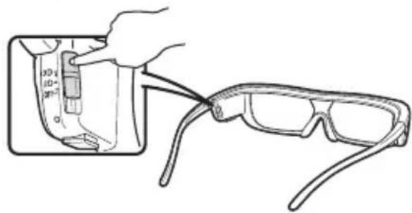 Line drawing of a hand holding a small object next to an open pair of eyeglasses (no text or symbols present)