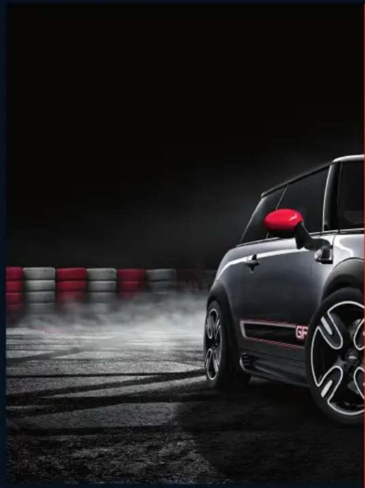Side view of a black and red Mini Cooper car on a dusty road with tire tracks in the background (no visible text or symbols)