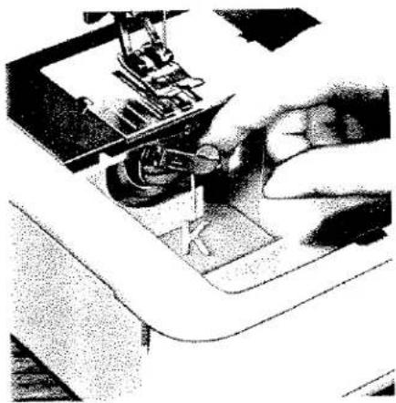 Gros plan sur une main actionnant un outil de machine à coudre (aucun texte ni symbole visible)