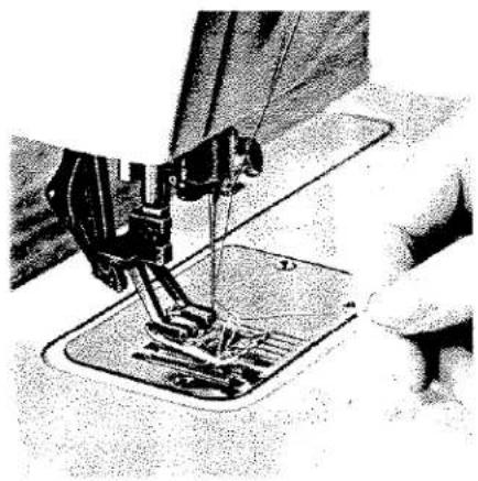 Gros plan sur l'aiguille d'une machine à coudre piquant le tissu, sans texte ni symboles visibles.