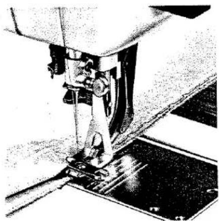 Gros plan sur une aiguille de machine à coudre en train de coudre une base métallique (aucun texte ni symbole visible).