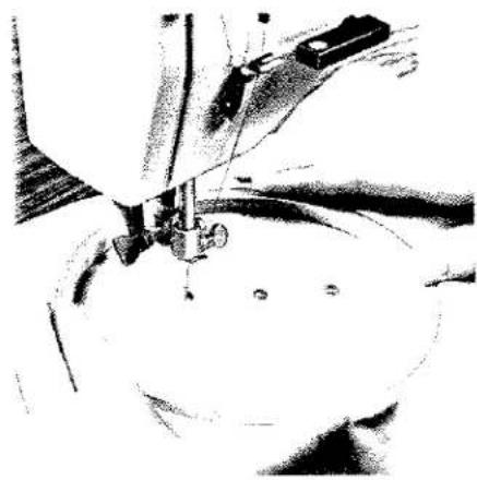 Gros plan d'une aiguille de machine à coudre piquant du tissu (aucun texte ni symbole visible)