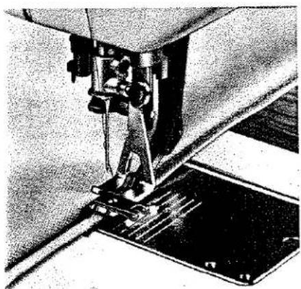 Gros plan d'une aiguille de machine à coudre piquant un tissu, sans texte ni symboles visibles