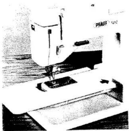 Photo en noir et blanc d'une machine à coudre en fonctionnement, aucun texte ou symbole visible sur la machine elle-même.