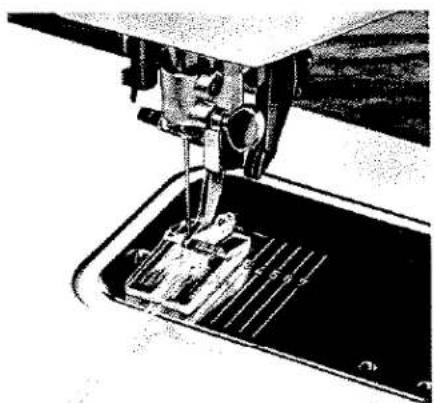 Gros plan d'une aiguille de machine à coudre cousant une pièce métallique (aucun texte ou symbole visible).