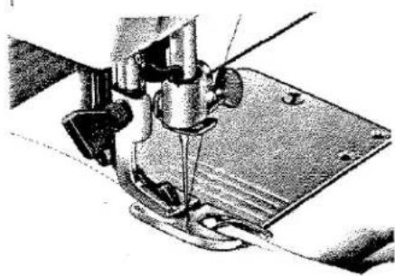 Gros plan sur l'aiguille d'une machine à coudre piquant une tôle (aucun texte ou symbole visible).