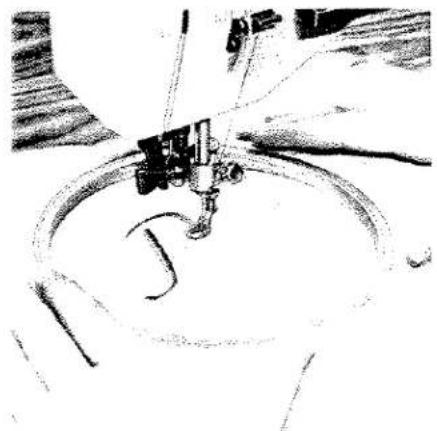 Gros plan d'une aiguille de machine à coudre cousant du tissu (aucun texte ou symbole visible).