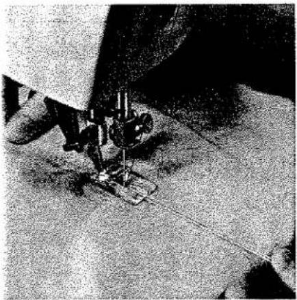 Gros plan d'une aiguille de machine à coudre piquant un tissu (sans texte ni symboles visibles)