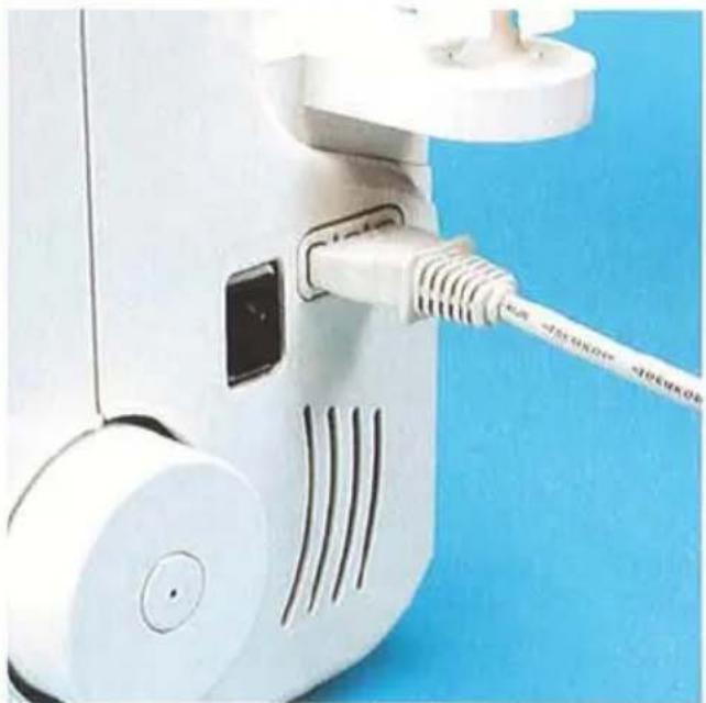 Gros plan d'un dispositif robotique blanc avec câble et ports attachés, sur un fond bleu (aucun texte ou symbole visible)