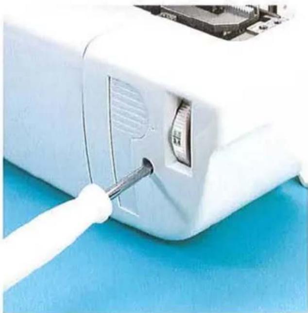 Gros plan d'un appareil électronique blanc avec un câble blanc inséré dans le port, montrant les composants internes et une surface bleue (aucun texte ou symbole visible)