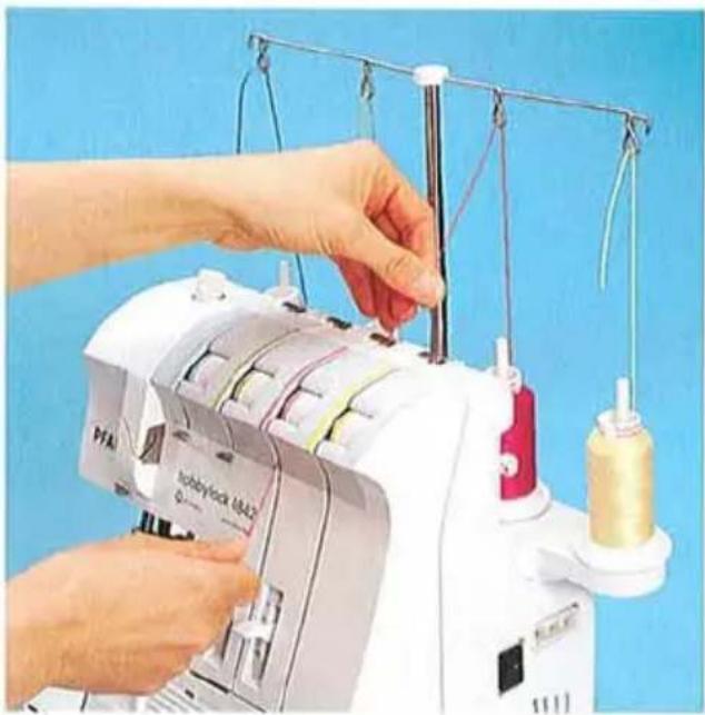 Gros plan de mains actionnant une machine à coudre avec une bobine de fil et du tissu (aucun texte ou symbole visible)