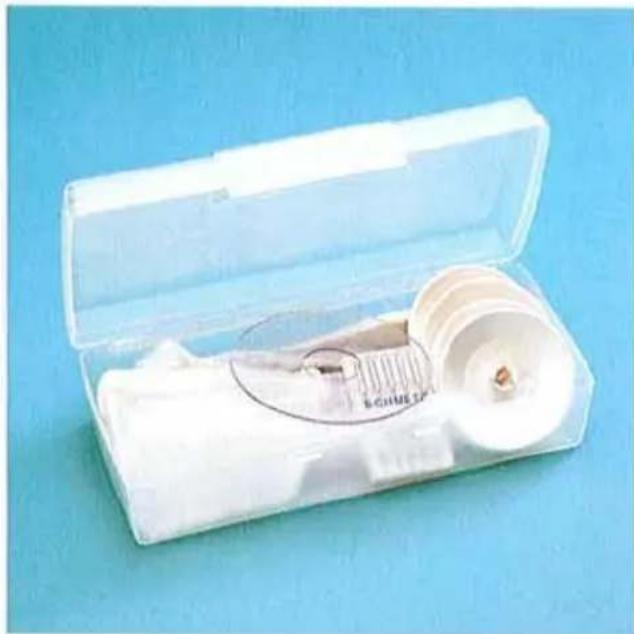 Dispositif médical en plastique ouvert avec un insert circulaire montrant un outil de mesure, posé sur une surface bleue (aucun texte ou symbole visible)