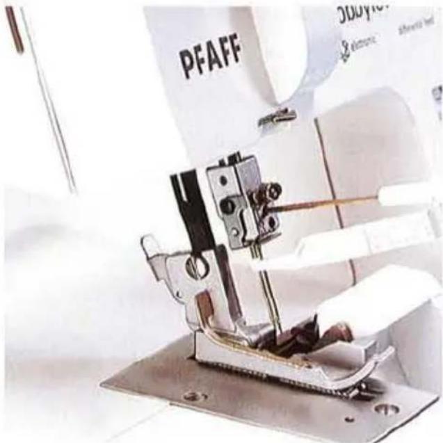 Gros plan d'une aiguille de machine à coudre cousant du tissu, avec la marque PFAFF visible (aucun texte lisible sur le corps de la machine).