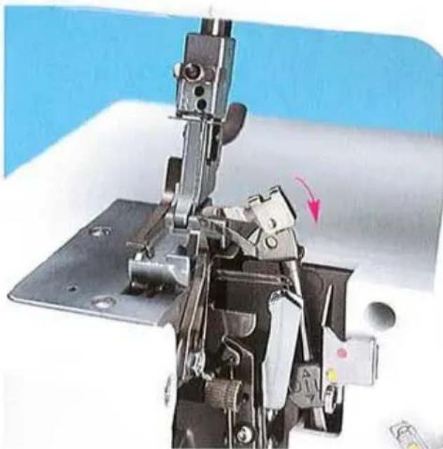 Gros plan sur l'assemblage de l'aiguille d'une machine à coudre avec des pinces métalliques et une flèche rouge indiquant un composant spécifique (aucun texte ou symbole visible)