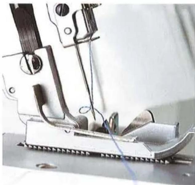Gros plan d'une aiguille de machine à coudre cousant du tissu, aucun texte ni symbole visible.