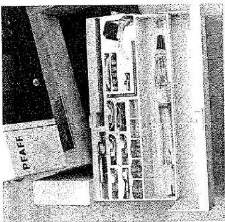 Photo en noir et blanc d'un dispositif mécanique avec plusieurs compartiments et une étiquette PFAFF (aucun texte lisible sur le sujet principal)