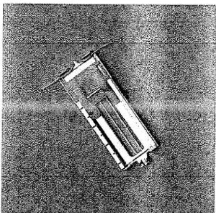 Vue de dessus d'un véhicule ou d'une plateforme rectangulaire sur une surface texturée (sans texte ni symboles visibles).