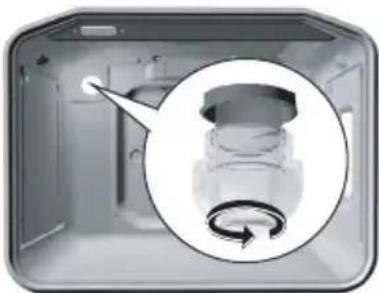 Interior view of a kitchen appliance with a magnified inset showing a button mechanism (no text or symbols visible).