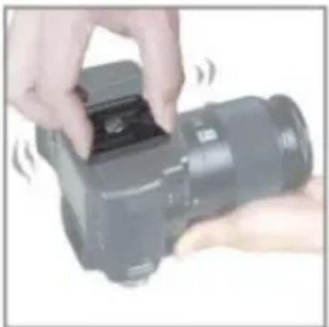 Close-up of hands holding a black DSLR camera with a small inset showing a lens (no visible text or symbols)