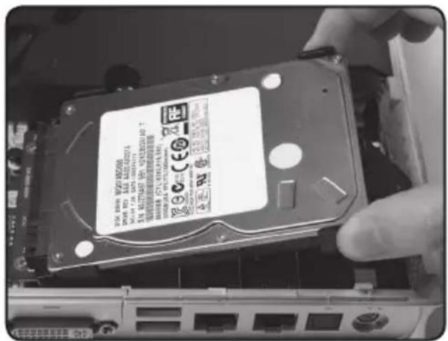 Close-up of a hand holding an internal hard disk drive with visible model number and certification marks
