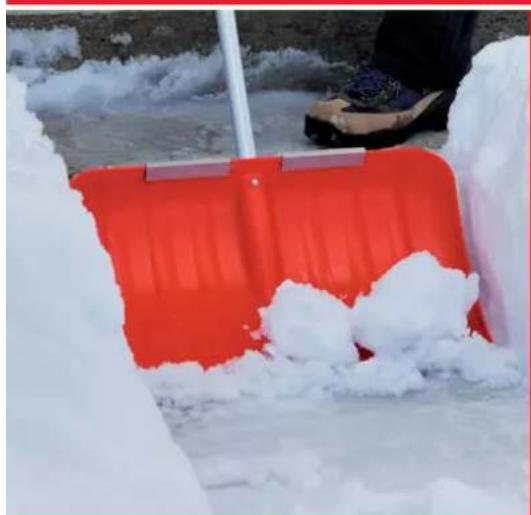 Red plastic push truck with white snow on a frozen surface, person standing nearby (no visible text or symbols)