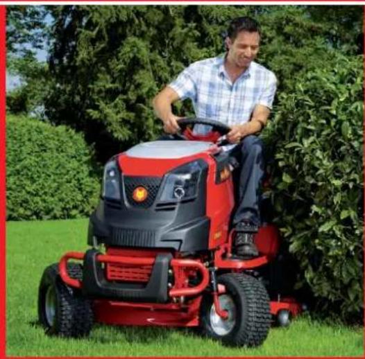 Man operating a red lawn mower on a grassy field, surrounded by green shrubs (no visible text or symbols)
