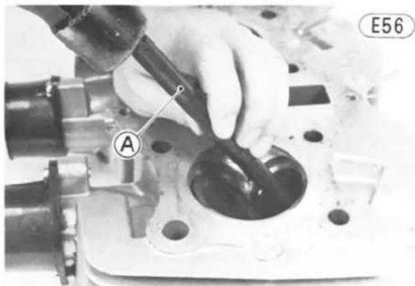 Close-up of a hand using a tool to inspect a mechanical component, labeled 'E56' with point A (no readable text or symbols beyond label)