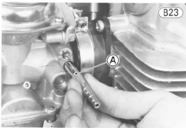 Close-up of a hand using a tool to adjust or install a mechanical component, labeled B23 (no visible text or symbols beyond label)