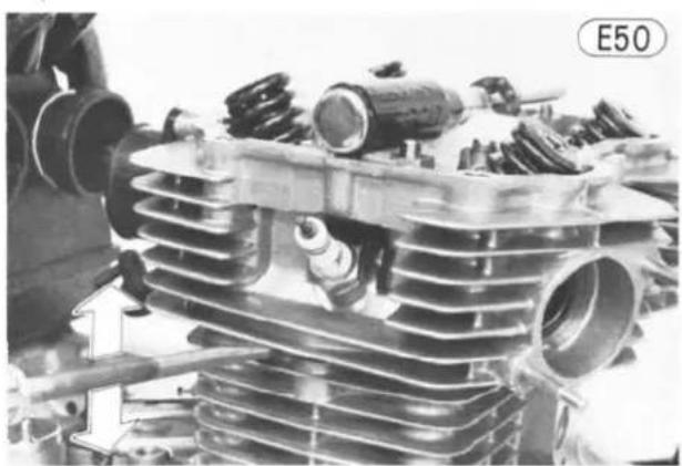 Close-up of an automotive engine cylinder head with visible cooling fins and internal components (no text or symbols)
