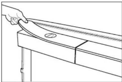 Line drawing of a hand holding a curved object on a wooden table, with no text or symbols present.