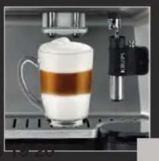 Close-up of a coffee machine with a glass mug filled with milk and a black Keros 15 brand applicator (no visible text or symbols)