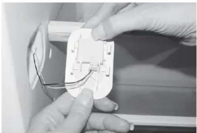 Close-up of hands installing or adjusting a white electrical socket with wires (no visible text or symbols)