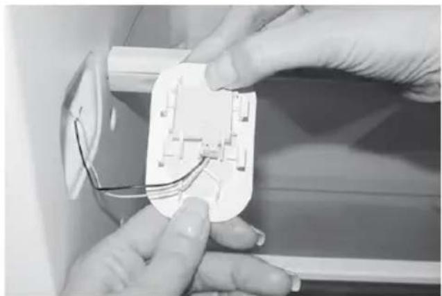 Close-up of hands installing or adjusting a white electrical socket with wires (no visible text or symbols)