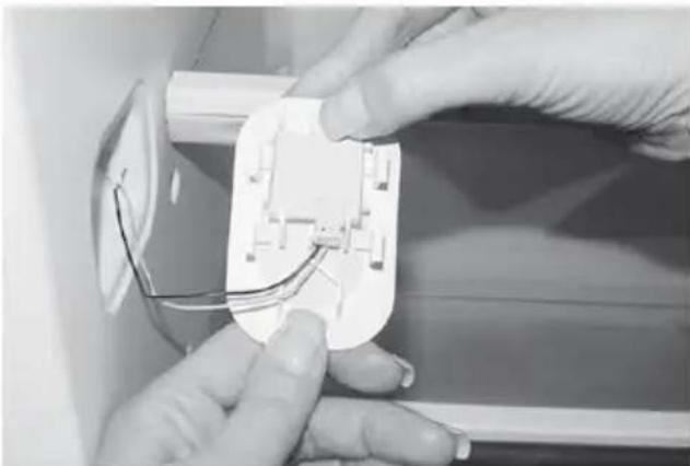 Close-up of hands installing or adjusting a white electrical socket with wires (no visible text or symbols)
